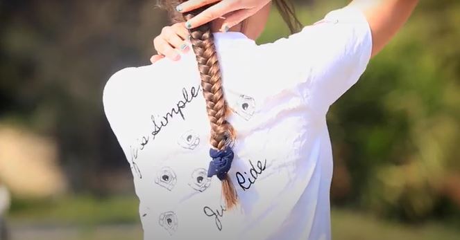Woman wearing equestrian-themed shirt, preparing for a ride; ideal fit for Cavallo hoof boots and horse care gear.