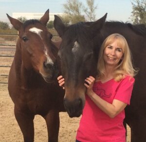 Woman with two horses in a paddock, highlighting equine care and Cavallo hoof boots benefits.