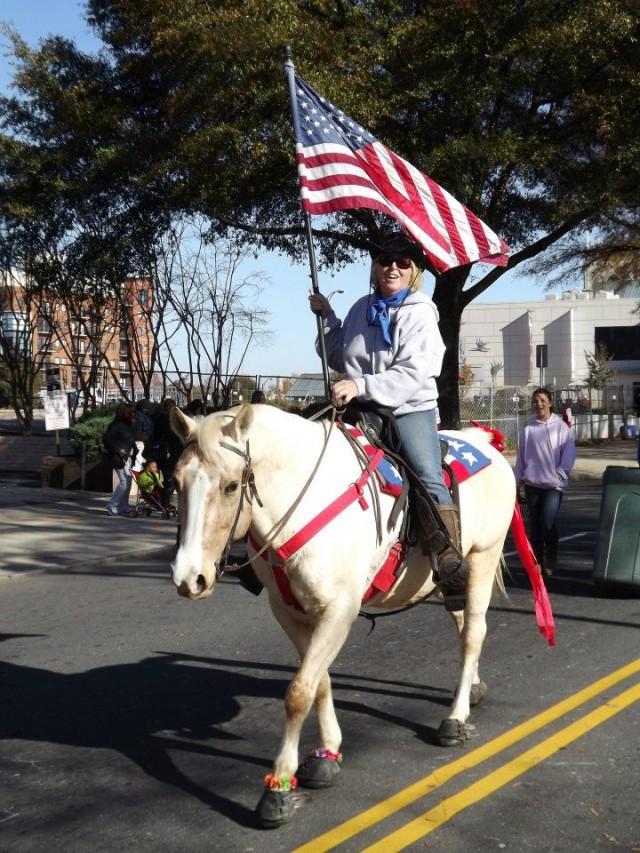 Rider on horse wearing Cavallo hoof boots, showcasing durable equine gear in a downtown parade setting.