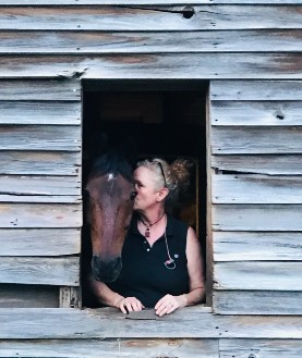 Woman with horse in barn, highlighting Cavallo hoof boots and equine care products for optimal horse health.