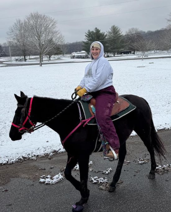 Rider on a horse in snow wearing Cavallo hoof boots, showcasing durable equine gear in winter conditions.
